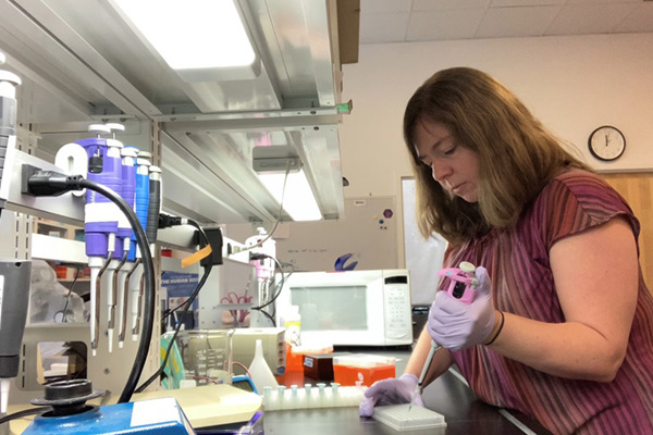 Woman in red shirt pipetting fluid into vials