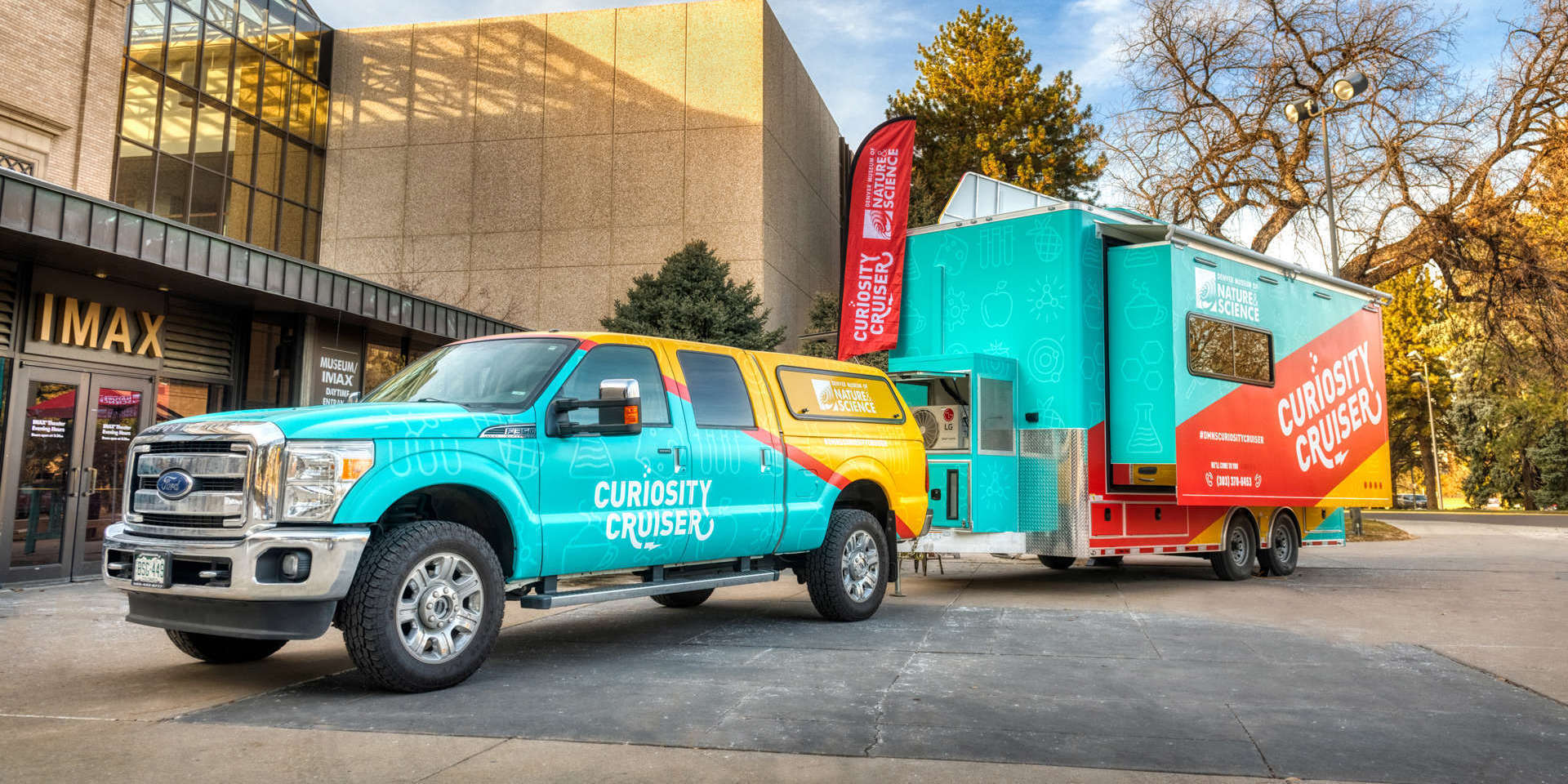 A colorful pickup truck and trailer with the Museum's Curiosity Cruiser branding