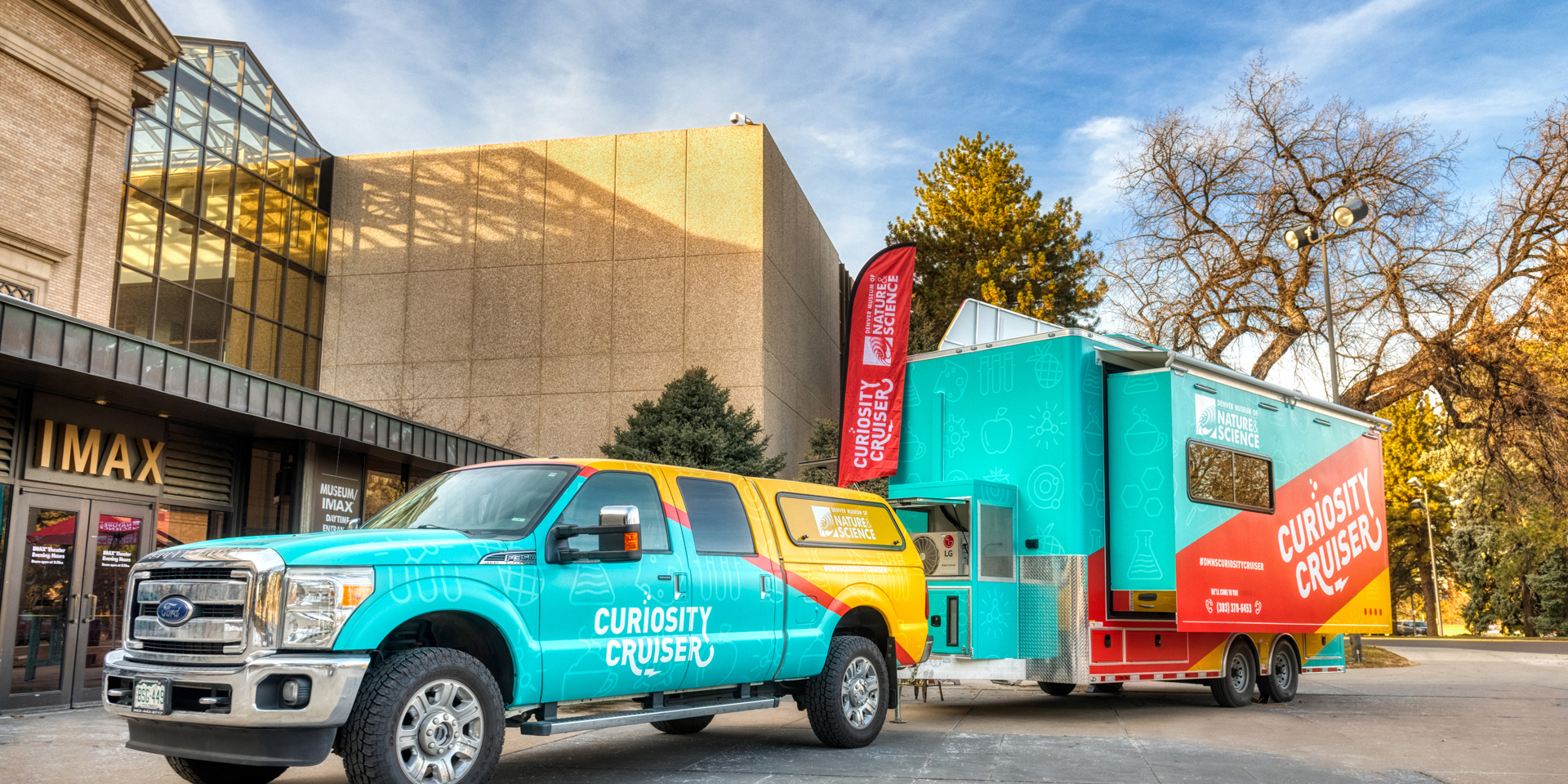 A colorful pickup truck and trailer with the Museum's Curiosity Cruiser branding