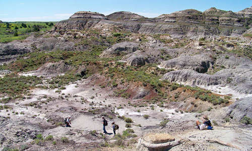 A wide image shot of the Hell Creek area with a couple of people walking in the foreground.