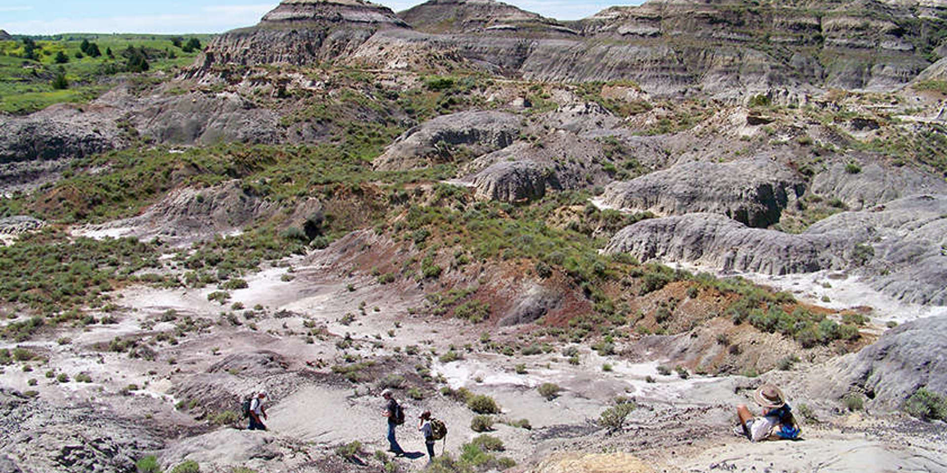 A wide image shot of the Hell Creek area with a couple of people walking in the foreground.