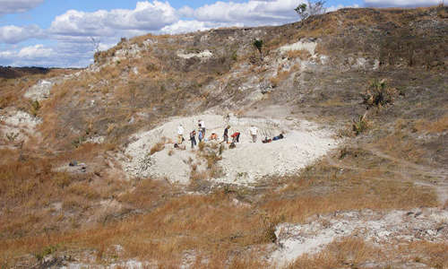 a far-away shot of the field site, with a group of people doing work on the site in the distance