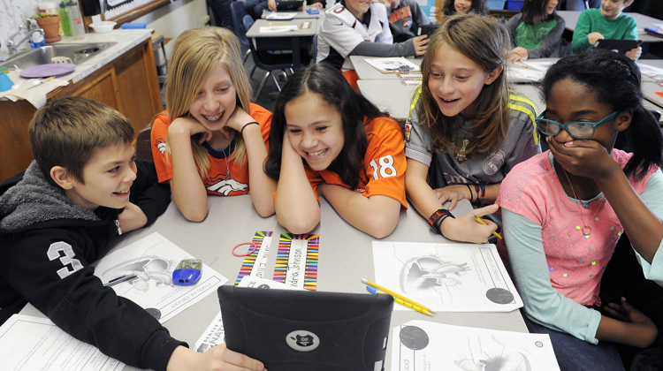 Students group around a tablet as they watch a live dissection with our "Virtual Heart" class.