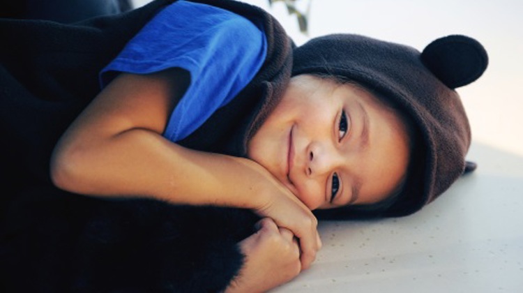 Young child laying on the floor, wearing a black bear costume